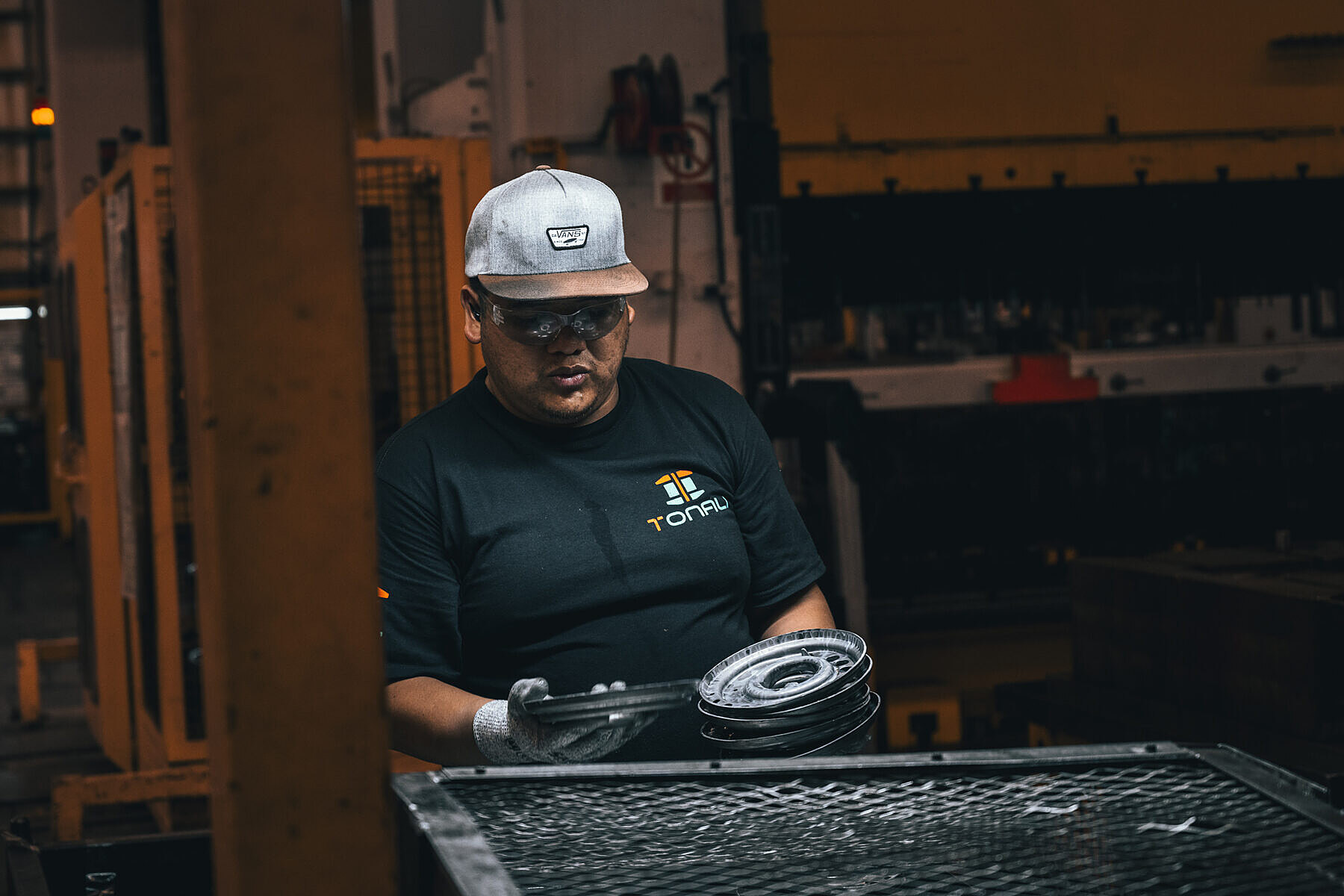 Operator unloading stamped steel parts at the press